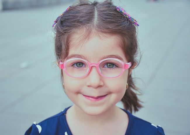 Une fillette portant des lunettes parfaitement ajustées. Les yeux se trouvent au centre de la monture qui ne dépasse pas trop au niveau des tempes.